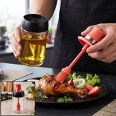 A person brushes oil on a grilled chicken leg using a glass oil dispenser with a red silicone brush.